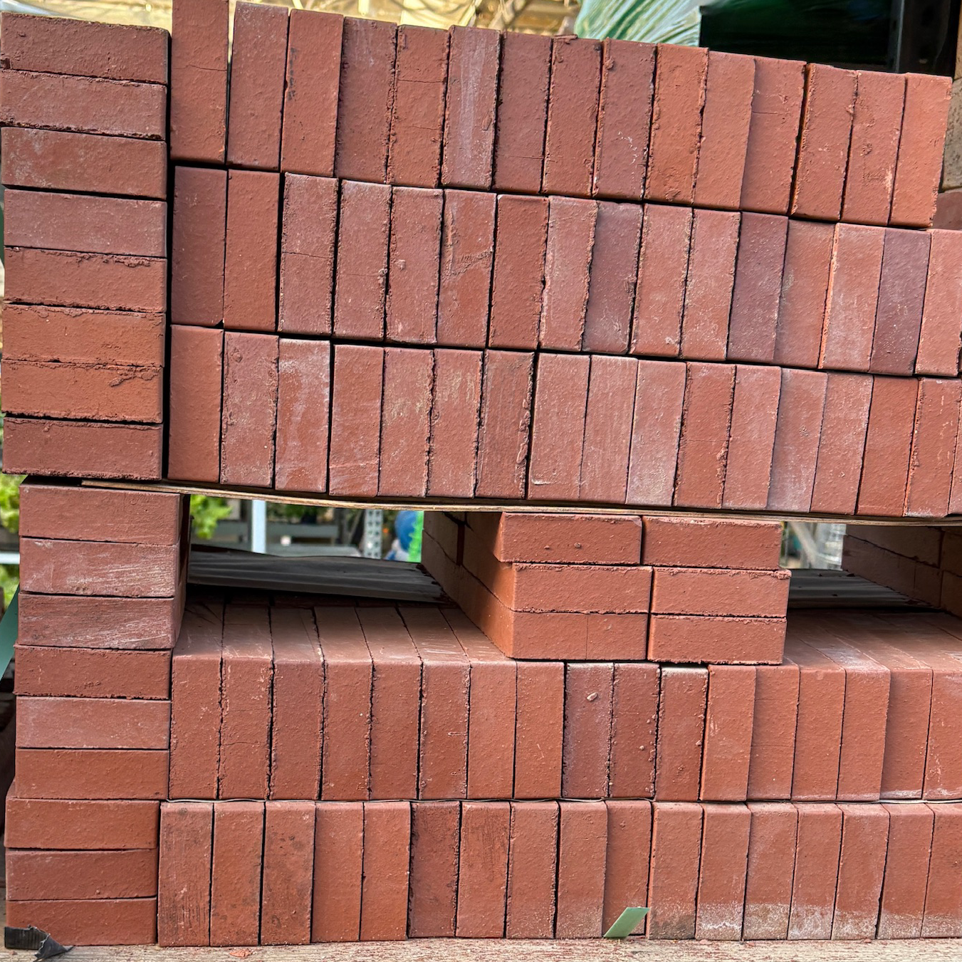 Stacks of red bricks on a pallet with a price tag in a warehouse setting.