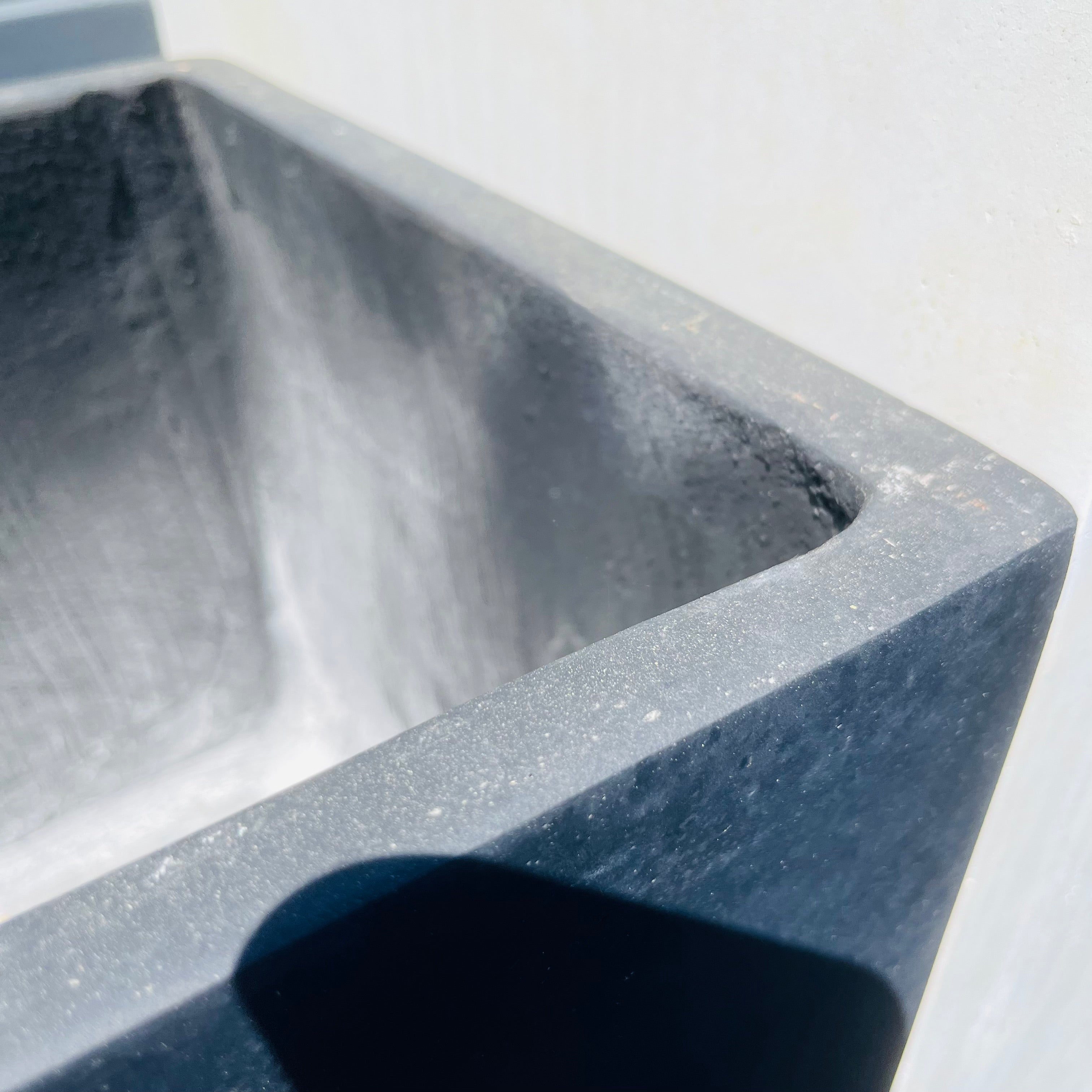 Close-up of a gray stone sink with a blurred background