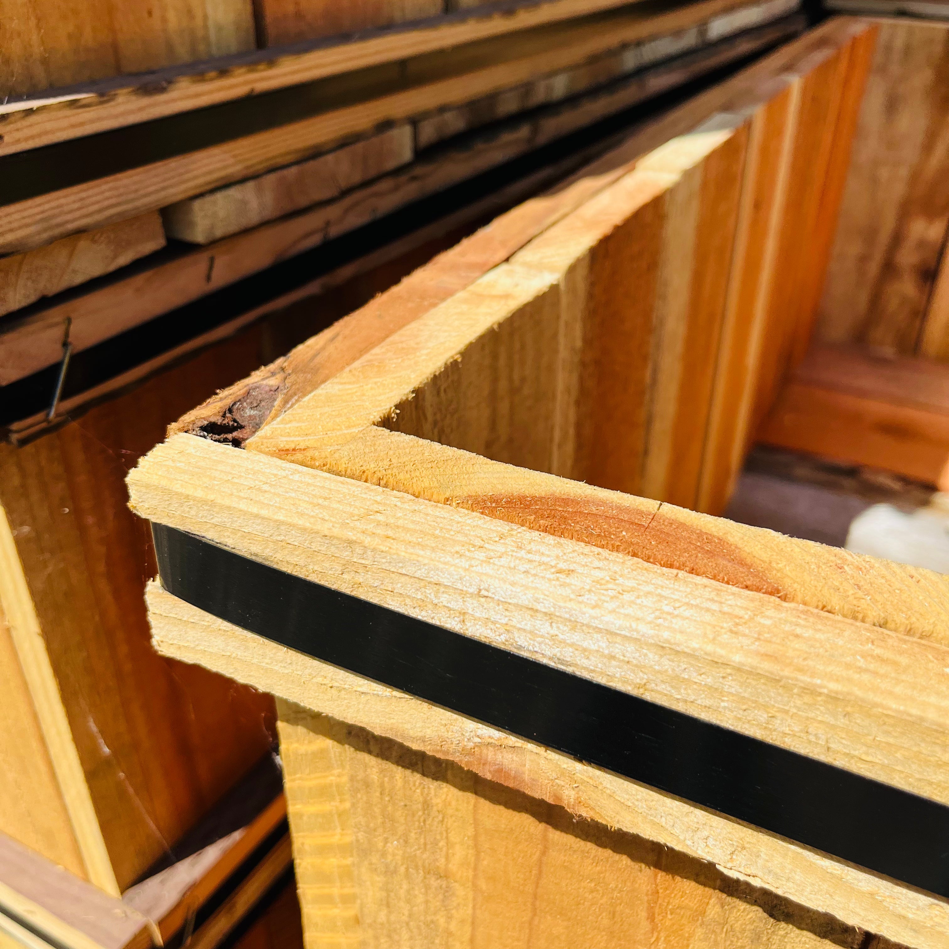 Close-up of wooden planks with a black strip, likely used for construction or flooring.