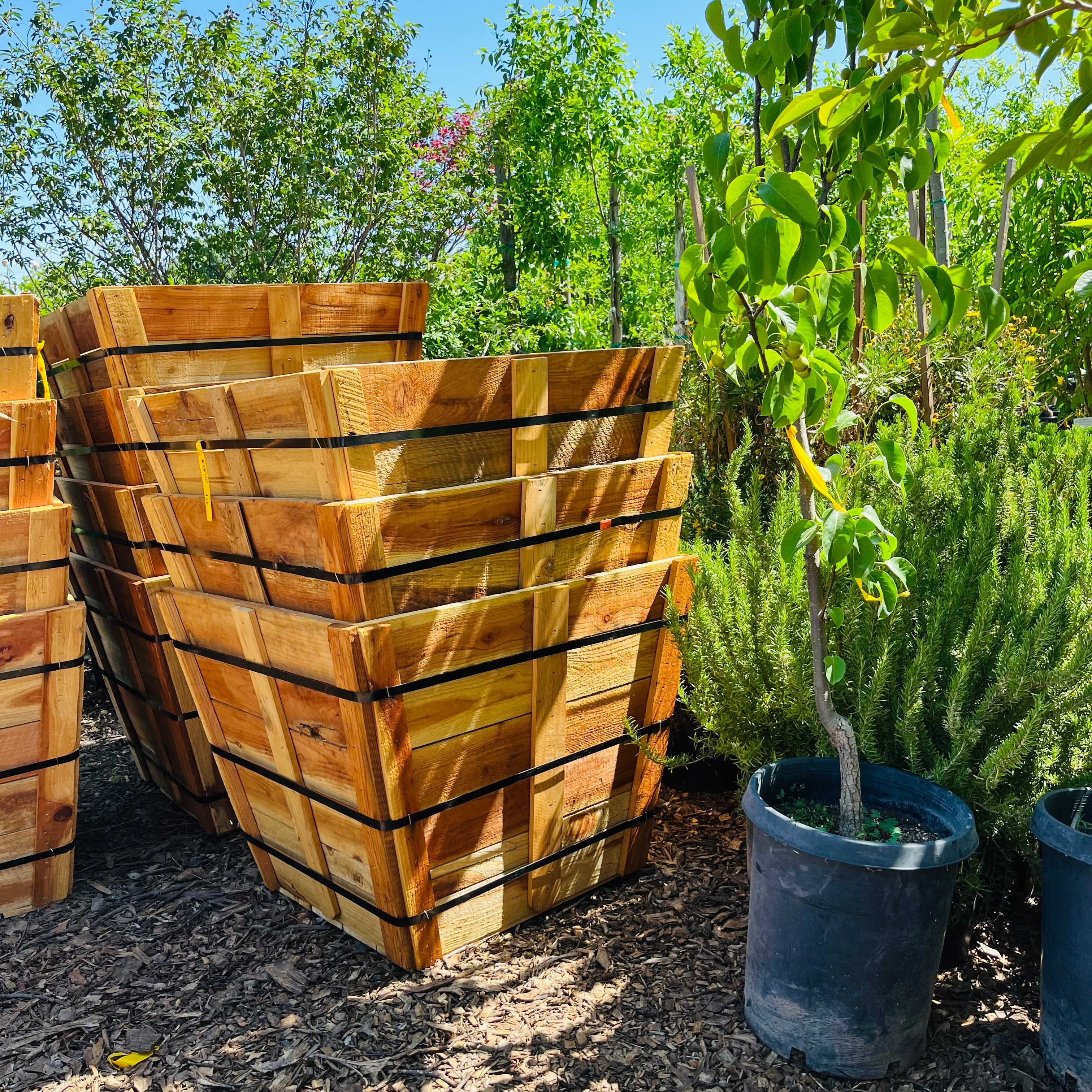 Stack of wooden planters with greenery in the background