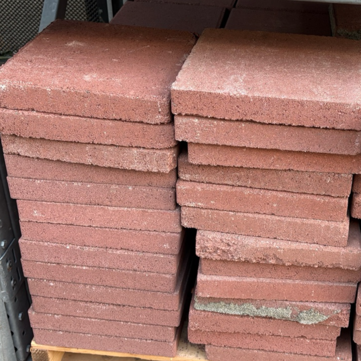 Stacks of red bricks on a wooden pallet in an indoor setting